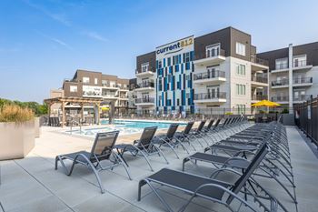 A pool area with chairs and a building with a sign that says "Current 812".